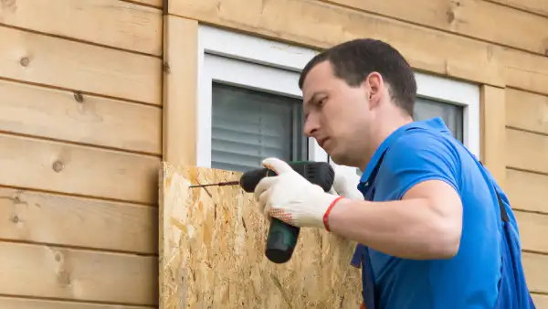 Business owner covering a window with plywood